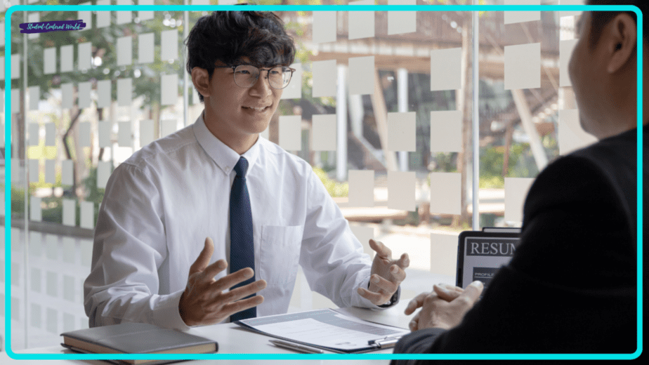 A person in a white shirt and tie sits at a desk, engaged in conversation with another individual. A document labeled Resume lies on the desk, possibly detailing teacher interview questions. A window with patterned decals adds a touch of ambiance to the background.