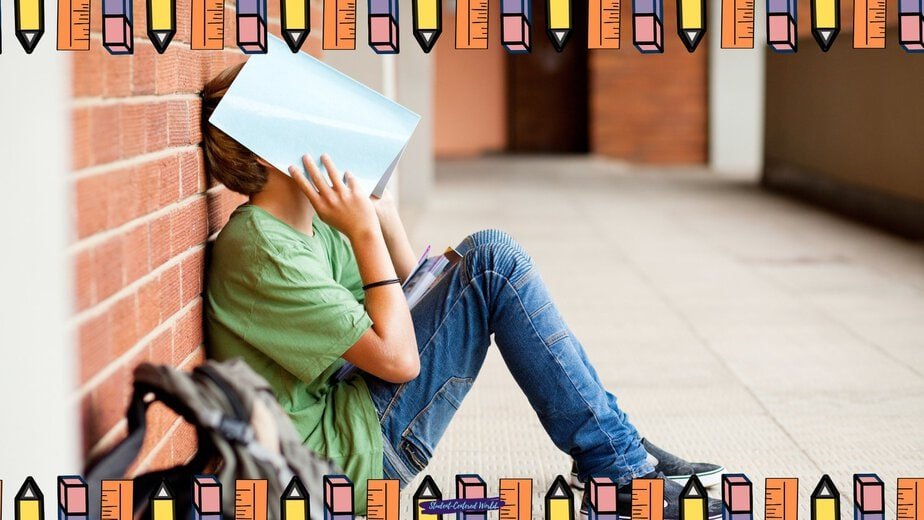 A student sits on the floor against a brick wall, holding a book over their face—clearly a Student Refusing to do Work. They wear jeans and a green shirt, with a backpack nearby. The image is bordered by a colorful pencil pattern.