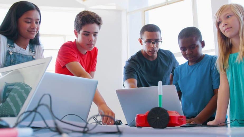 A group of students and a teacher gather around a table with laptops and a small robot, working together on a STEM project in a bright classroom what is the theory of student-centered