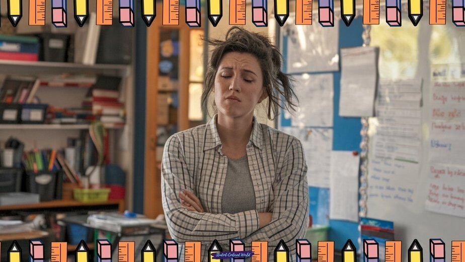 A woman stands in a classroom with arms crossed and eyes closed, looking frustrated. Colorful pencil border frames the image. Classroom materials and posters are visible in the background.