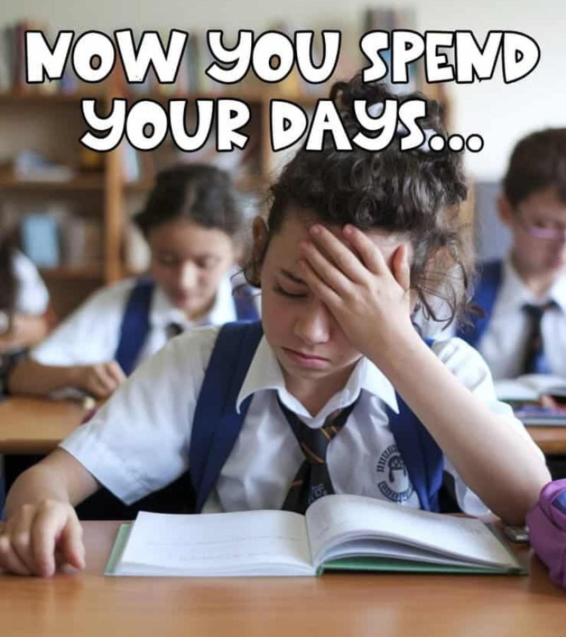 A student in a school uniform sits at a desk, looking stressed with one hand on her forehead. An open book is in front of her. Other students are visible in the background. Text on the image reads, NOW YOU SPEND YOUR DAYS...